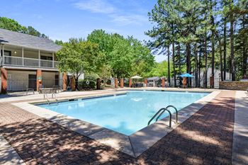 a swimming pool with trees and a building in the background at 300 Riverside Apartments, Georgia